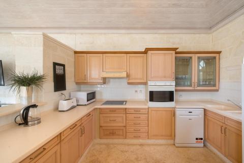 Spacious kitchen at Forest Hills 23 in Royal Westmoreland, Barbados, featuring warm wooden cabinetry, modern appliances, and sleek countertops.