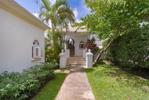 Tropical entrance to Forest Hills 23, featuring a beautifully landscaped pathway, lush greenery, and a charming island-style villa exterior.