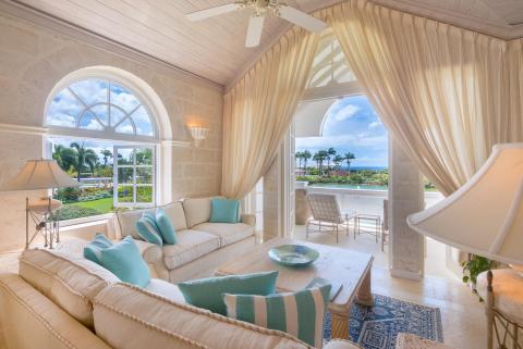 Bright and airy living room at Forest Hills 23, Barbados, with arched windows, comfortable seating, and a patio overlooking lush gardens and the ocean.
