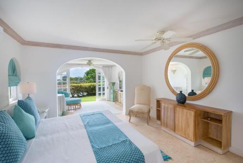 Bright and inviting master bedroom at Forest Hills 23, featuring a cozy lounge area, garden views, and elegant Caribbean-inspired decor.