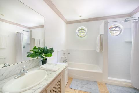 Bright and modern guest bathroom at Forest Hills 23, Barbados, featuring a bathtub, walk-in shower, and elegant marble vanity.