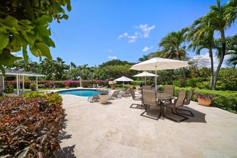 Spacious pool deck with comfortable seating, loungers, and umbrellas, surrounded by lush gardens at Ixora Royal Westmoreland, Barbados