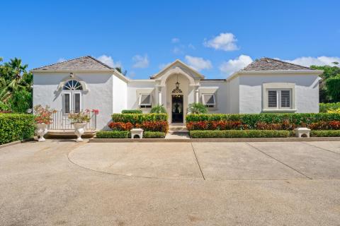 The elegant front entrance of Ixora Villa at Royal Westmoreland, framed by lush gardens and tropical plants