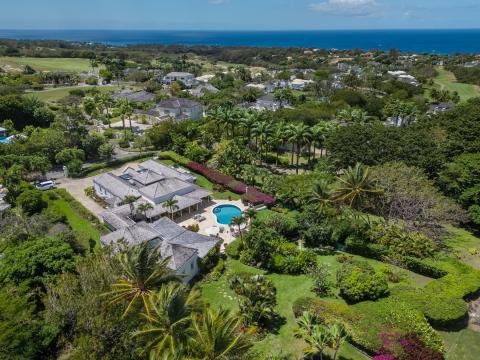 Tranquil pool area at Ixora Villa with surrounding gardens, lounge chairs, and parasols for relaxation