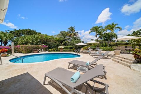 Loungers and poolside area with turquoise pool and tropical landscaping at Ixora, Royal Westmoreland, Barbados