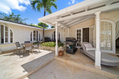 Relaxing outdoor space at Ixora with a BBQ grill, chairs, and a small palm tree, perfect for enjoying the tropical climate at Royal Westmoreland, Barbados