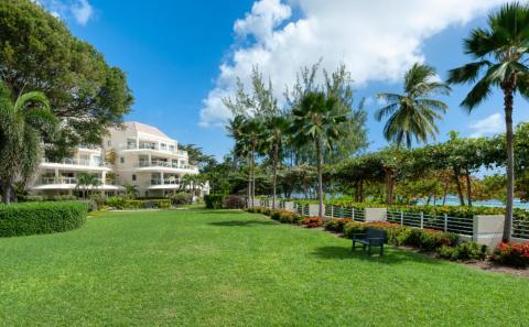 A scenic view of the manicured lawns and private beach access gate leading to the white sandy shores of Barbados’ South Coast.