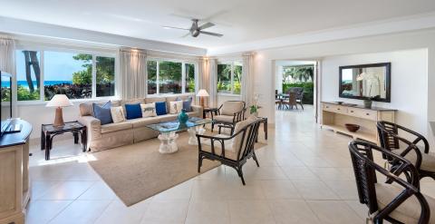 A beautifully designed living room at Palm Beach 101, Barbados, with plush seating, natural light, and large windows showcasing stunning ocean views.