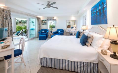 A tranquil master bedroom at Palm Beach 101 in Barbados, featuring a king-size bed, stylish coastal decor, and direct access to a private patio.