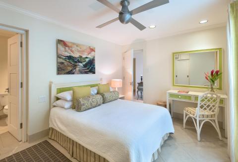 A serene second bedroom at Palm Beach 101, Barbados, featuring a queen-size bed, pastel decor, and a private en-suite bathroom.
