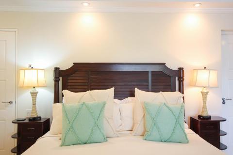 Comfortable king-sized bed in the master suite of Palm Beach 109, Barbados, featuring elegant wooden furnishings and soft lighting.
