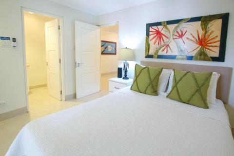 Bright and airy queen bedroom at Palm Beach 109, Barbados, with soft bedding, a modern ceiling fan, and stylish tropical decor.