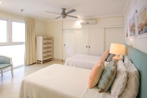 Spacious third bedroom at Palm Beach 109, Barbados, with twin beds, soft lighting, and built-in storage.