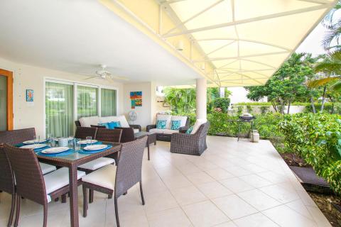 Expansive covered patio at Palm Beach 109, Barbados, overlooking lush tropical gardens with dining and lounge areas.