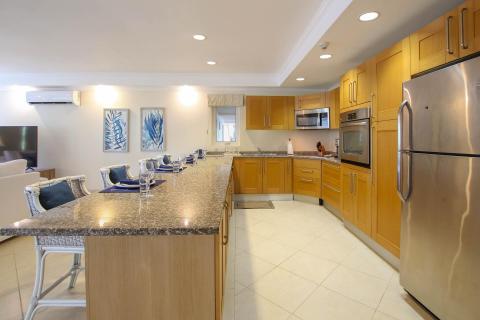 Fully equipped kitchen at Palm Beach 109, Barbados, featuring wood cabinetry, granite countertops, and top-of-the-line appliances.