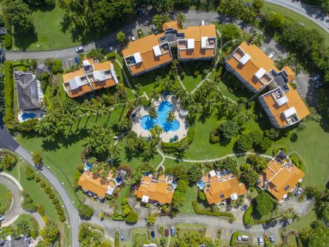 Aerial view of Sugar Hill Resort, Barbados, featuring the lush landscaped grounds, tropical palm trees, and the central pool area, with the Seabreeze Penthouse nestled among luxury villas, showcasing its prime location in this upscale resort.