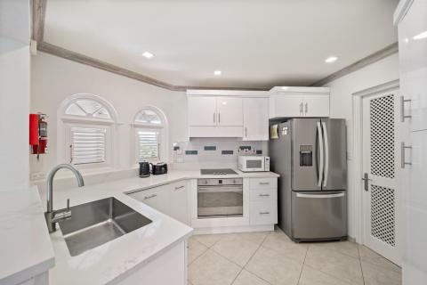 Modern kitchen in Sunshine View Penthouse, Sugar Hill Resort, Barbados, featuring stainless steel appliances, sleek white cabinetry, and a large sink, providing a functional and stylish space for cooking and entertaining.