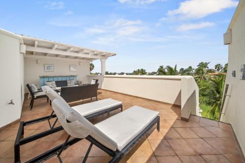 Rooftop terrace of Sunshine View Penthouse, Sugar Hill Resort, Barbados, featuring sun loungers, cozy seating area, and partial sea views, perfect for sunbathing or evening relaxation with picturesque surroundings.