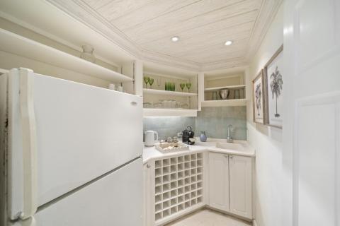 A small but charming wet bar area at Seascape villa in Barbados, complete with a refrigerator, open shelving, and a cozy setup for entertaining during a beachfront holiday rental.