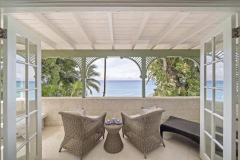A private balcony at Seascape beachfront villa in Barbados, offering wicker seating and breathtaking views of the Caribbean Sea, perfect for relaxing mornings or sunset cocktails during a holiday rental.