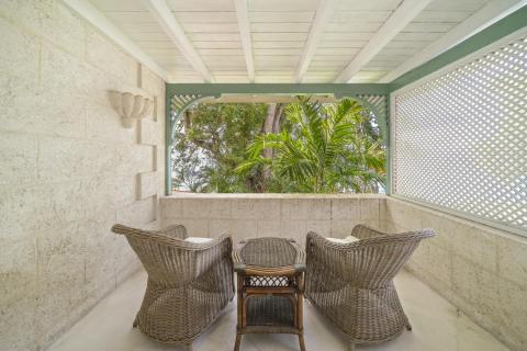 Image of a private balcony overlooking lush greenery at Seascape, Barbados: A private balcony adorned with wicker seating, overlooking lush tropical gardens and offering a peaceful retreat for morning coffee or evening relaxation during your stay at Seascape, Barbados.