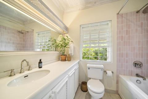 Image of the en-suite bathroom with a garden view at Seascape, Barbados: A modern en-suite bathroom with soft pink tiles, a large vanity, and a window that frames the lush greenery outside, creating a tranquil retreat for guests in this Barbados holiday villa.